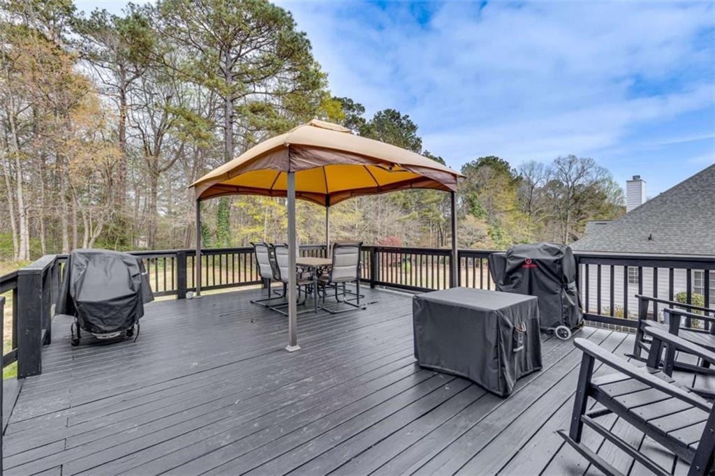1148 Maple Creek Ridge Loganville, GA 30052 - Photo 42 of 46 a view of a roof deck with table and chairs under an umbrella with wooden floor