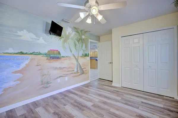 en empty room with wooden floor and ceiling fan