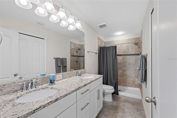 a en suite bathroom with a granite countertop sink a toilet and a mirror