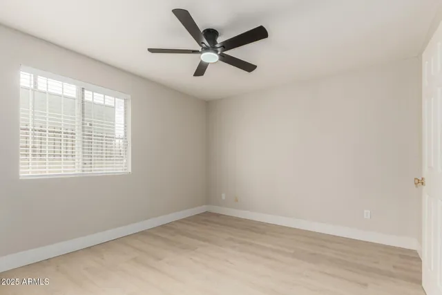 an empty room with a window and ceiling fan