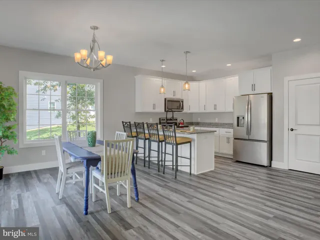 a kitchen with stainless steel appliances wooden floors refrigerator dining table and chairs