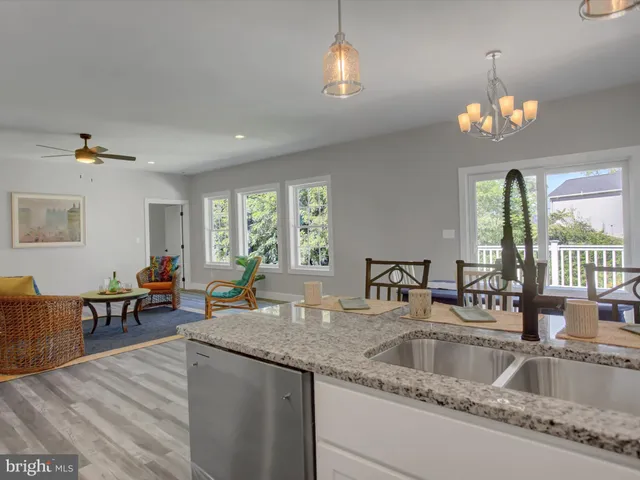 a kitchen with a stove a sink dishwasher a dining table and chairs with wooden floor