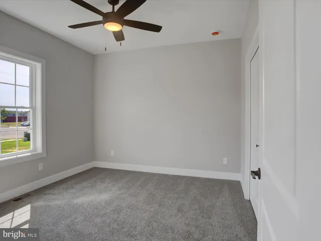 an empty room with windows and fan