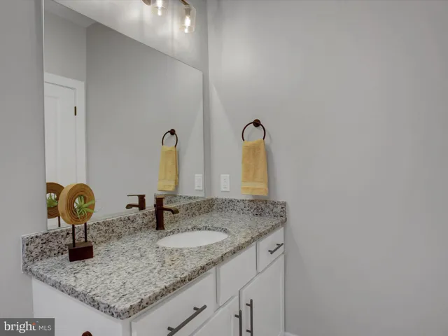 a bathroom with a granite countertop sink and a mirror