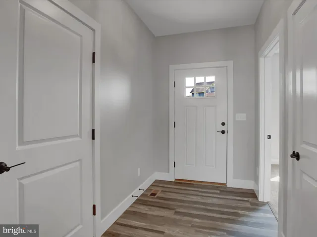 a view of a hallway with wooden floor and a bathroom