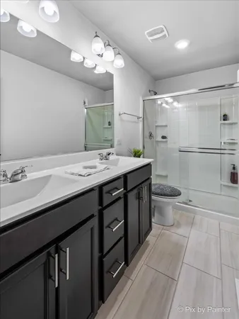 a spacious bathroom with a granite countertop sink a toilet a mirror a vanity and shower