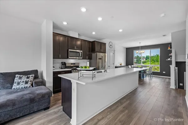 a large white kitchen with a large window a oven a counter space and a refrigerator