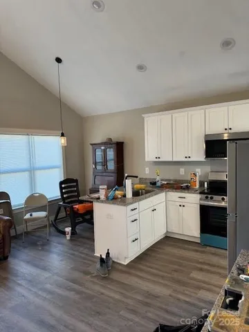 a kitchen with granite countertop a stove and white cabinets
