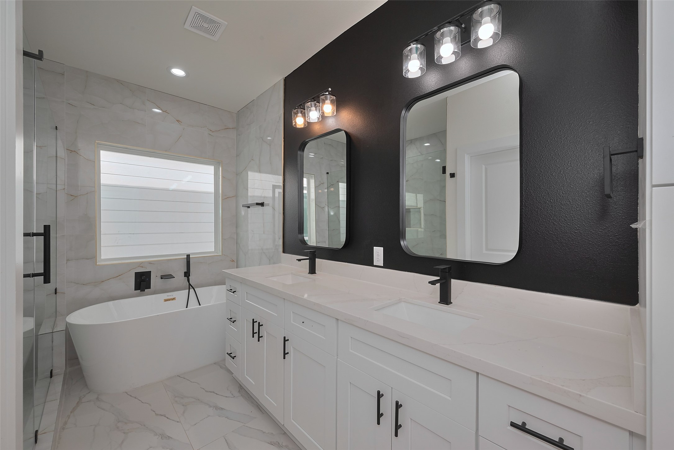 2422 Dalview Street Houston, TX 77091 - Photo 13 of 24 Enjoy the sleek, high-end look of the
primary bathroom, boasting a dual
sink vanity, freestanding soaking tub,
and glass-enclosed shower, all
complemented by premium finishes.