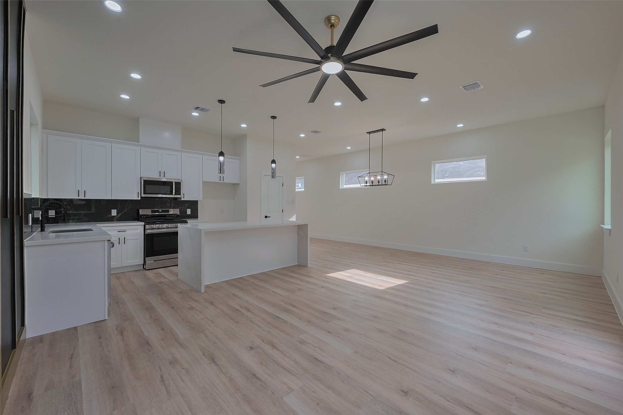 2422 Dalview Street Houston, TX 77091 - Photo 5 of 24 A wider view of the first floor showcases the beautiful light laminate wood flooring, which adds warmth and durability to the space.