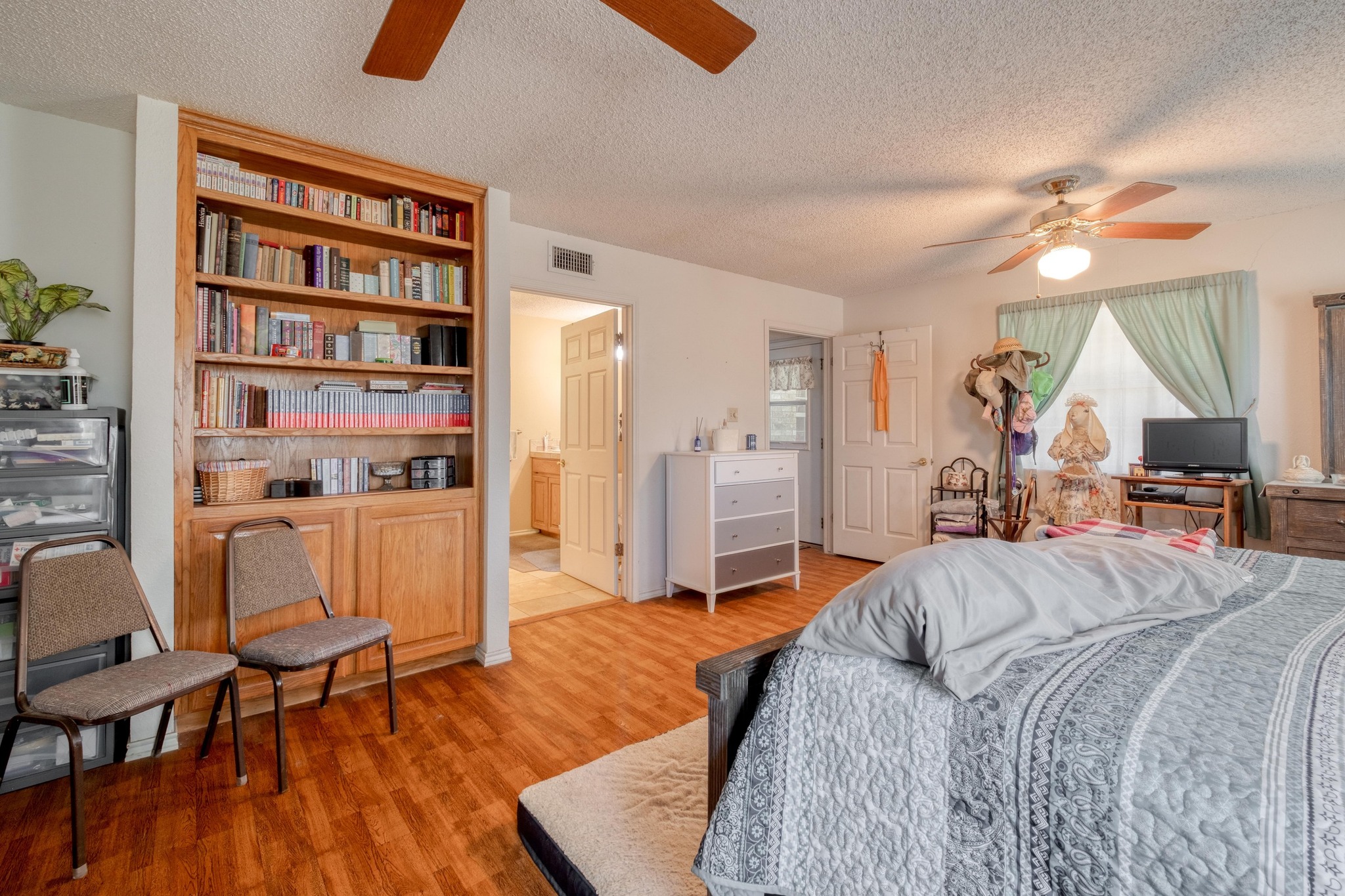153 Pleasant Grove Road Elgin, TX 78621 - Photo 18 of 34 Bedroom with a textured ceiling, a ceiling fan, light wood finished floors, and ensuite bathroom