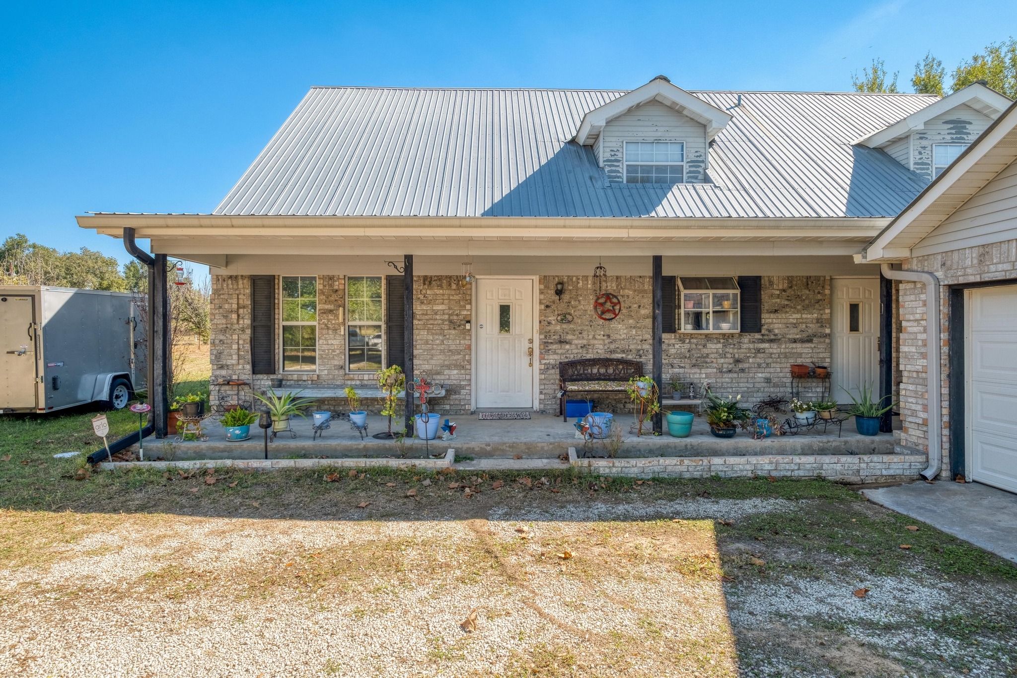 153 Pleasant Grove Road Elgin, TX 78621 - Photo 5 of 34 View of front of house featuring a porch, an attached garage, a metal roof, and brick siding