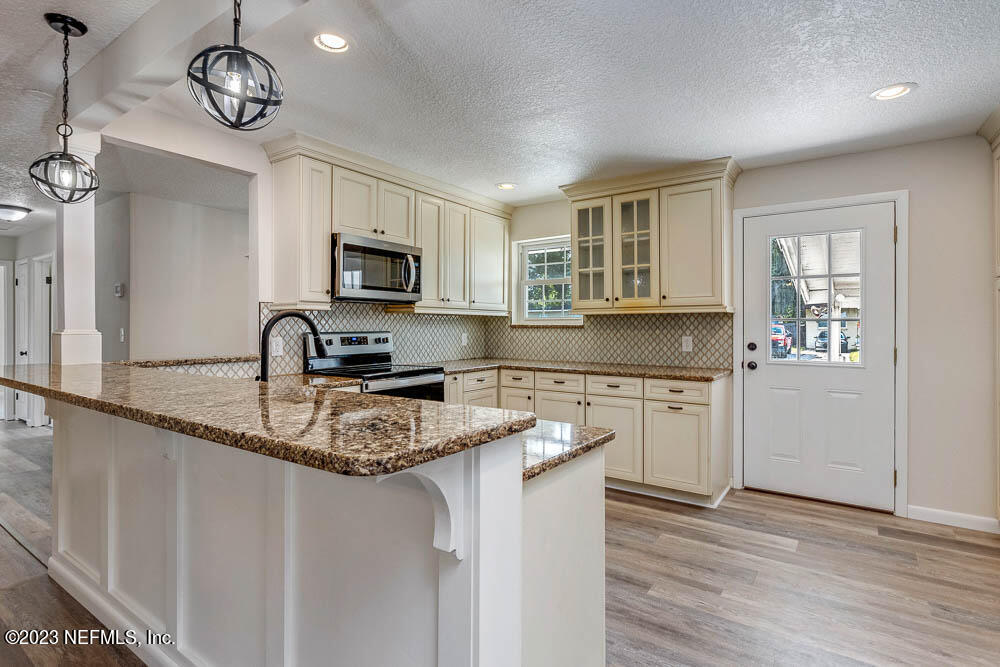 a kitchen with stainless steel appliances granite countertop a sink dishwasher a stove top oven a refrigerator with grey cabinets and wooden floor