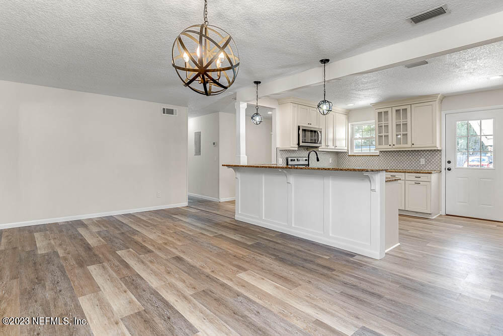 4066 Ferrarra Street Jacksonville, FL 32217 - Photo 10 of 25 a kitchen with stainless steel appliances granite countertop a sink a stove top oven a chimney cabinets and wooden floor