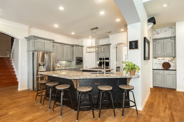 a kitchen with kitchen island granite countertop a sink center island stainless steel appliances and cabinets