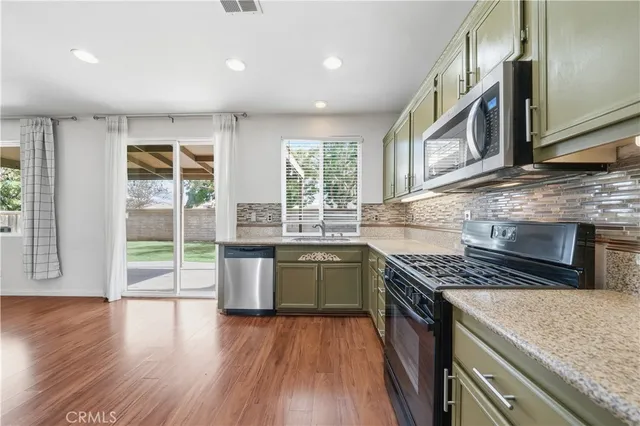 a kitchen with stainless steel appliances granite countertop hardwood floor sink stove and wooden cabinets