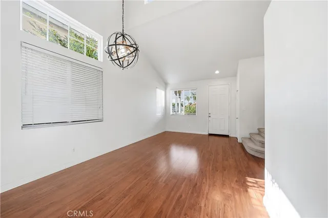 an empty room with wooden floor mirror and windows
