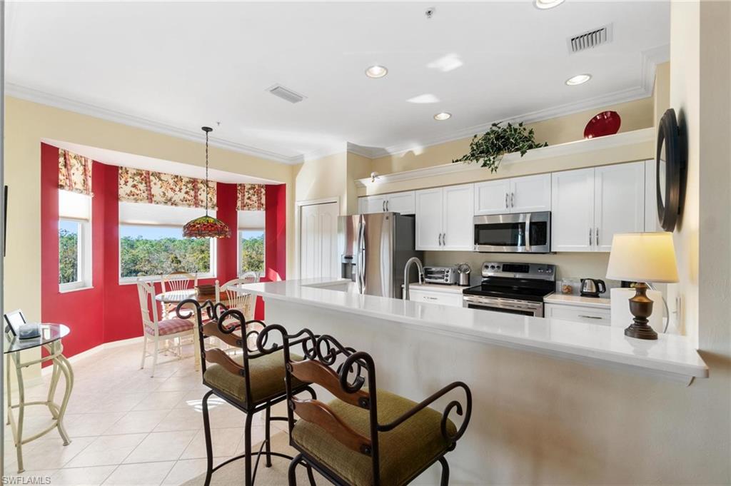 8610 Cedar Hammock Circle, Unit 1242 Naples, FL 34112 - Photo 27 of 50 a kitchen with stainless steel appliances granite countertop a stove top oven a sink dishwasher a dining table and chairs with wooden floor