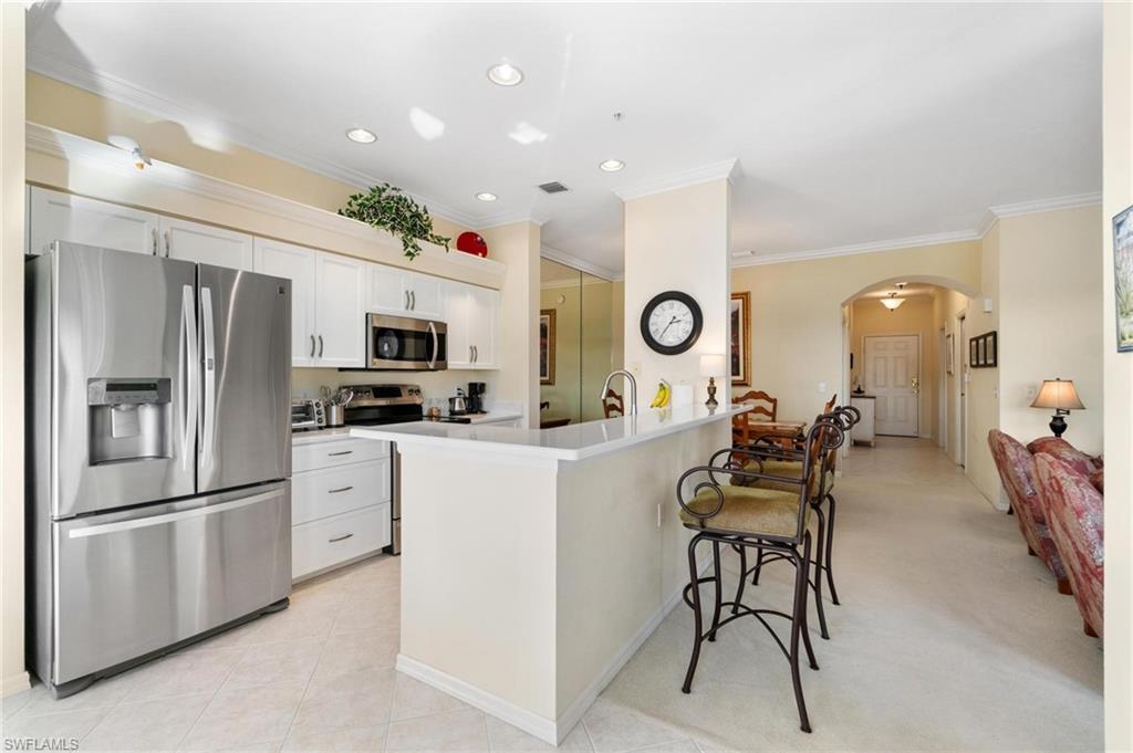 8610 Cedar Hammock Circle, Unit 1242 Naples, FL 34112 - Photo 31 of 50 a kitchen with stainless steel appliances kitchen island granite countertop a refrigerator and microwave