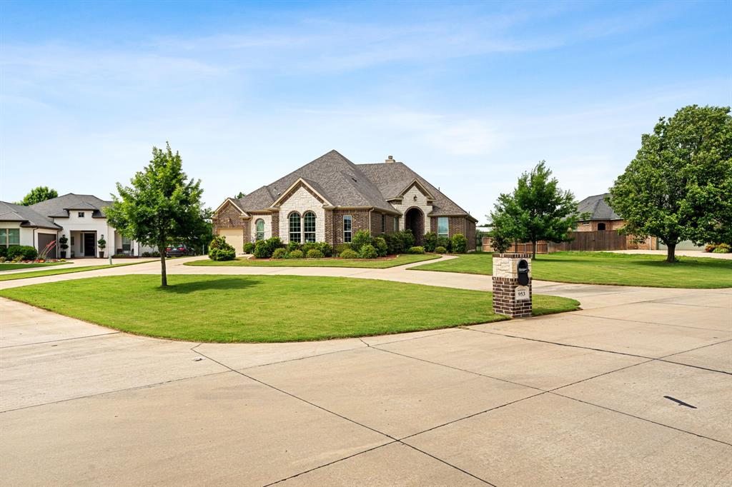 Front view of home with brick and stone structure, pathway for front door, and circular driveway.