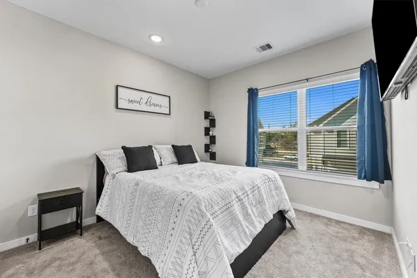 a bedroom with a large bed and a flat tv screen on dresser