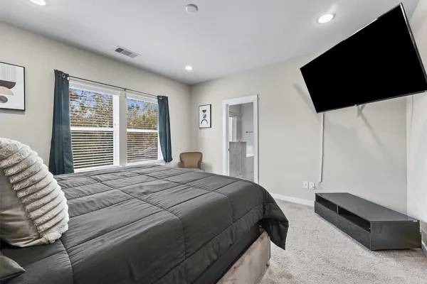 a bedroom with a bed a flat screen tv and windows