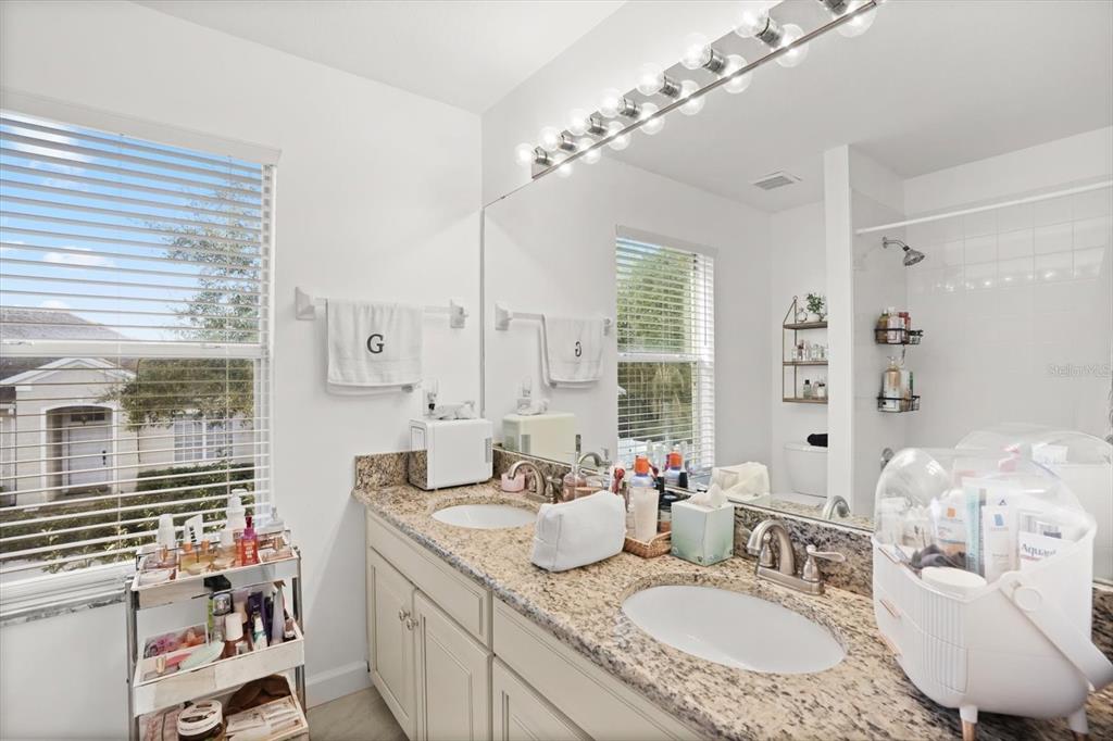 248 Longhirst Loop Ocoee, FL 34761 - Photo 18 of 30 a bathroom with a granite countertop sink a large mirror and a shower