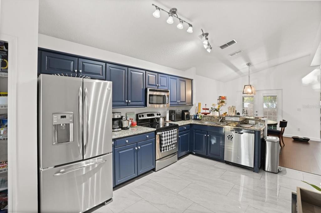 248 Longhirst Loop Ocoee, FL 34761 - Photo 9 of 30 a kitchen with stainless steel appliances granite countertop a refrigerator a stove a sink dishwasher a refrigerator a oven with white cabinets and wooden floor