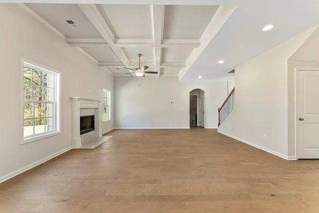 a view of a livingroom with a fireplace a ceiling fan and windows
