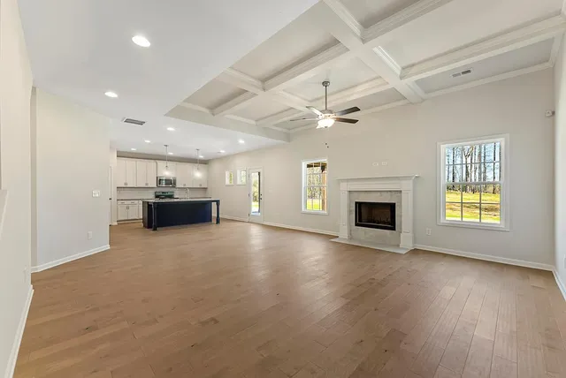 an empty room with kitchen fireplace and a ceiling fan