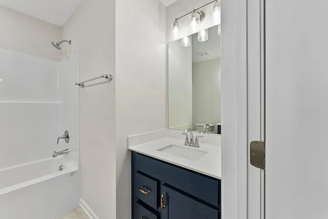 a bathroom with a bath tub sink mirror and shower