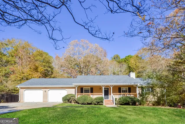 a view of a yard in front of a house with plants and large tree
