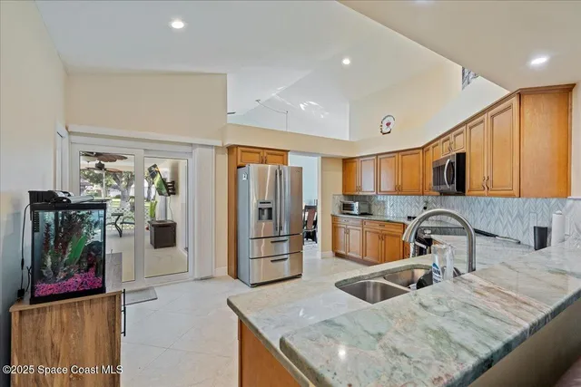 a kitchen with stainless steel appliances granite countertop a sink and a refrigerator