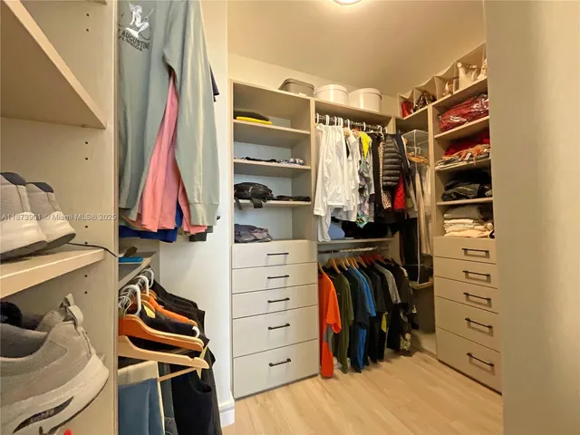 a view of walk in closet with clothes and shoes