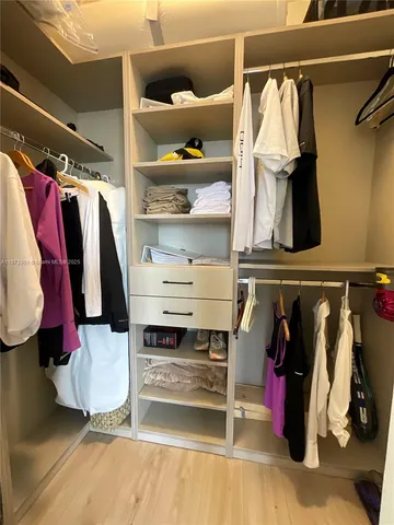 a view of walk in closet with clothes and shoes