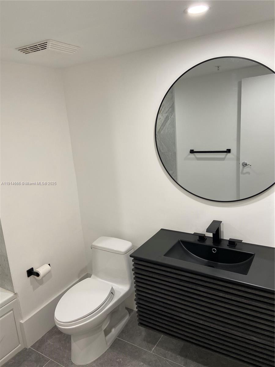 31 Southeast 5th Street, Unit 2103 Miami, FL 33131 - Photo 12 of 17 a bathroom with a toilet a sink and mirror
