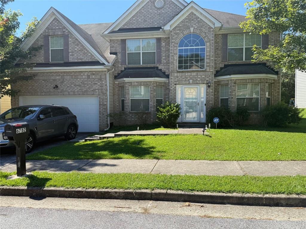 6782 Mancha Street Atlanta, GA 30349 - Photo 1 of 2 a front view of a house with a yard and garage