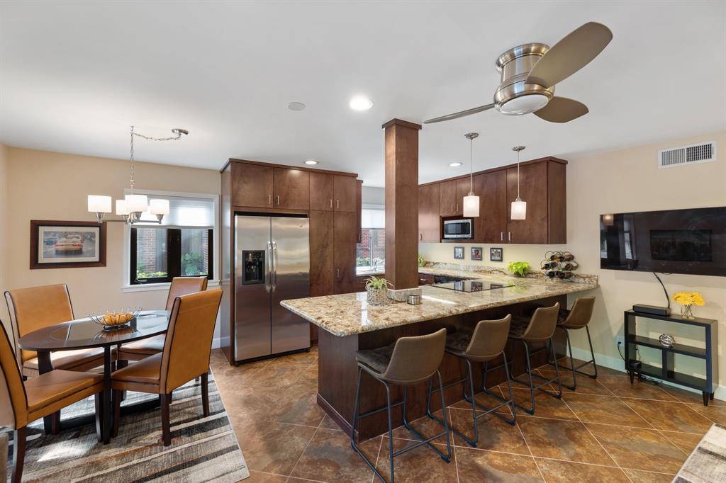 a kitchen with stainless steel appliances granite countertop a table chairs sink and cabinets