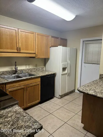 a kitchen with granite countertop a refrigerator and a sink