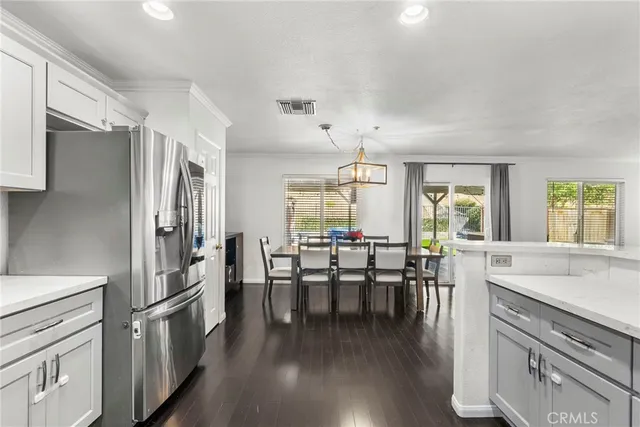 a kitchen with stainless steel appliances a dining table chairs stove refrigerator and cabinets