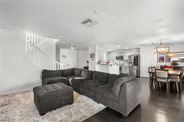 a living room with furniture with kitchen view and a wooden floor