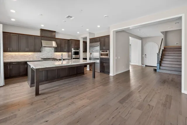 a large kitchen with stainless steel appliances granite countertop a lot of counter space and wooden floors