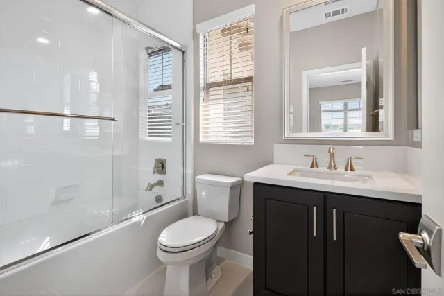 a bathroom with a toilet a sink a mirror a bathtub and window