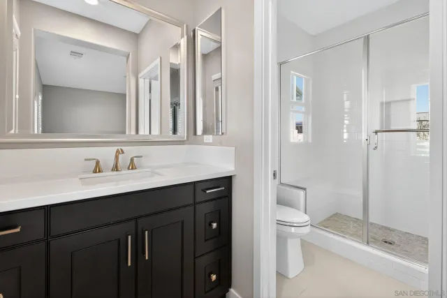 a bathroom with a shower sink vanity mirror and toilet