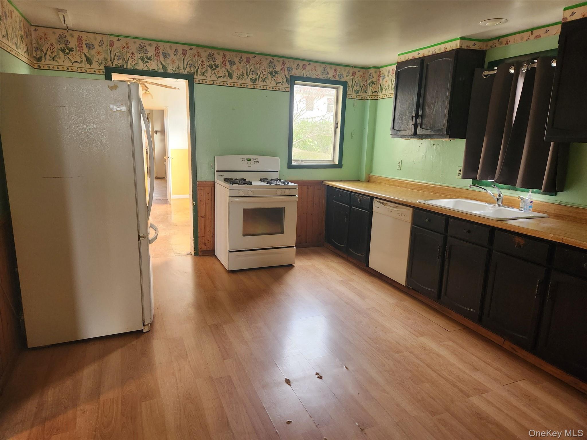19 Grove Street Beacon, NY 12508 - Photo 11 of 38 Kitchen with white appliances, light countertops, light wood-style flooring, and dark cabinetry
