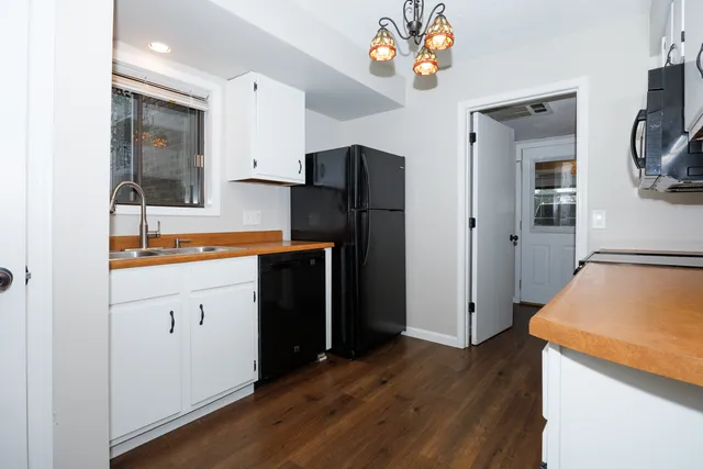 a kitchen with stainless steel appliances granite countertop a refrigerator a sink dishwasher and wooden cabinets with wooden floor