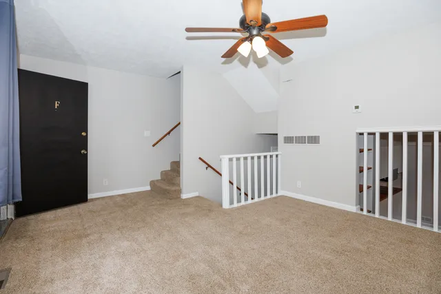 a view of a livingroom with a ceiling fan and stairs