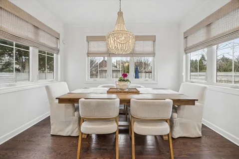 a dining room with wooden floor a chandelier a wooden table and chairs