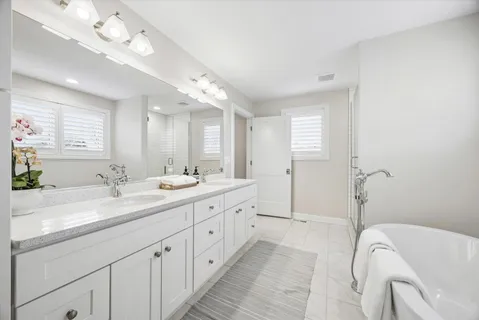 a spacious bathroom with a double vanity sink mirror and bathtub