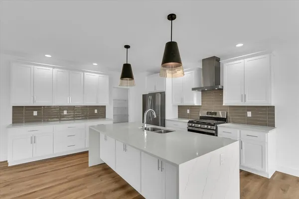 a kitchen with stainless steel appliances a sink a stove and a wooden floors
